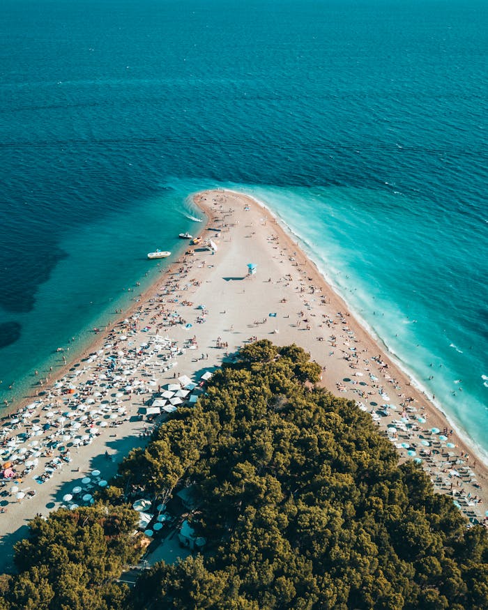 gallery-1 Stunning aerial view of Zlatni Rat beach in Bol, Croatia, showcasing turquoise waters and sandy peninsula.