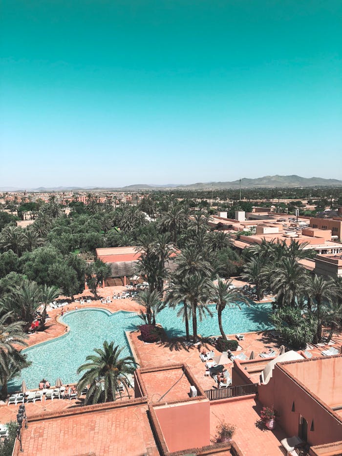 gallery-6 Aerial view of a luxurious tropical resort featuring a scenic swimming pool amidst lush greenery.