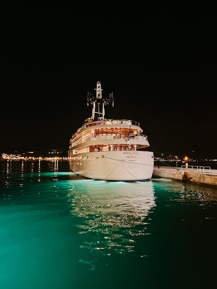 gallery-2 A luxurious yacht docked at night with illuminated waters providing a serene maritime ambiance.