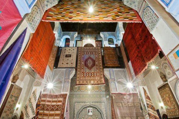 pexels photo 28582586 28582586 A captivating display of vibrant Moroccan rugs hanging in the historic Medina of Fès, Morocco.