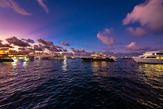 Opulent-Mediterra-Luxury-Yachts-Night-Charter Illuminated luxury yachts docked at night in a Mediterranean marina under a vibrant twilight sky, showcasing exclusive charter options.