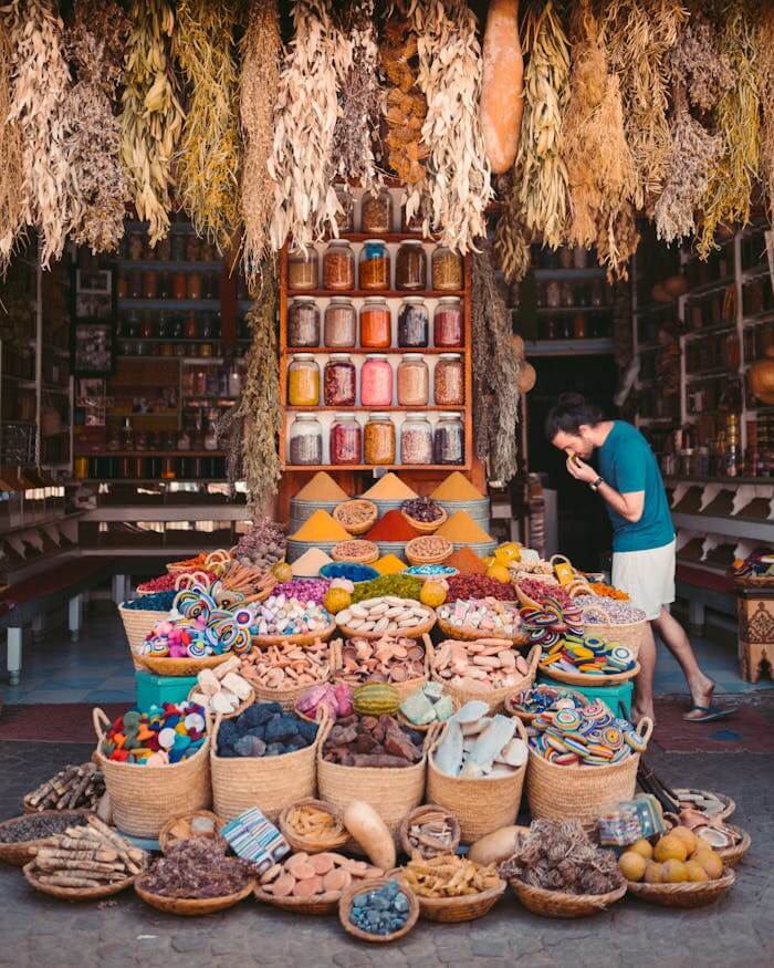 Moroccan Spice Souk - Mediterranean Sensory & Luxury Experience Wide view of a vibrant Moroccan spice souk featuring hanging dried herbs from the ceiling